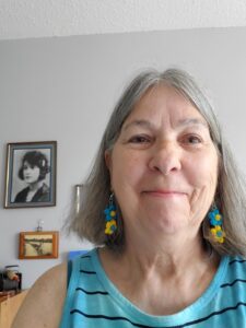 Headshot of Terry Brinson. Terry is smiling and wearing crocheted blue and yellow flower earrings.